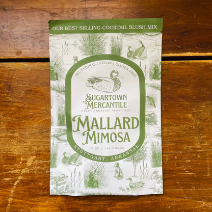 A packaged cocktail mix labeled 'Mallard Mimosa' by Sugartown Mercantile, featuring an illustration of a duck and foliage.
