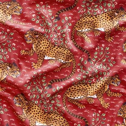 Fabric with leopards and leaves on a red background