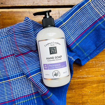 A pump bottle of Linden & London hand soap resting on a blue and red plaid cloth. Hand soap that smells like lavender, patchouli and lemon