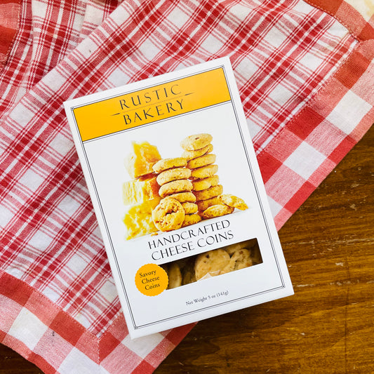 A packaged box of Savory Cheese Coins on a red and white checkered cloth.